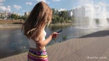 夏天的一天，在公园散步时，迷人的女人把黑色的智能手机扔在<strong>鹅卵石</strong>街上